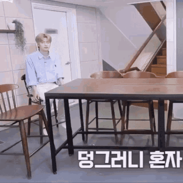 a man is sitting at a table in a room with chairs and stairs .