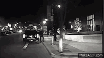 a black and white photo of a person walking down a street at night .