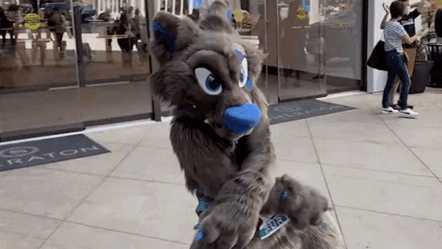 a furry mascot is standing on a sidewalk in front of a hotel .