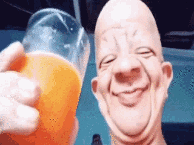 a bald man is holding a glass of orange juice and smiling