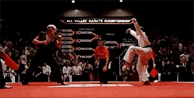 a karate match is taking place in front of a crowd .