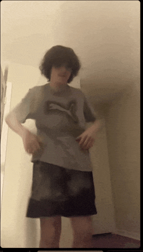 a young man wearing a puma shirt and shorts is standing in a room
