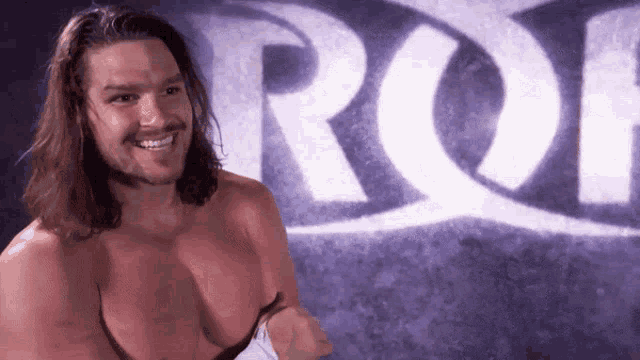 a shirtless man with long hair is smiling in front of a sign that says rof