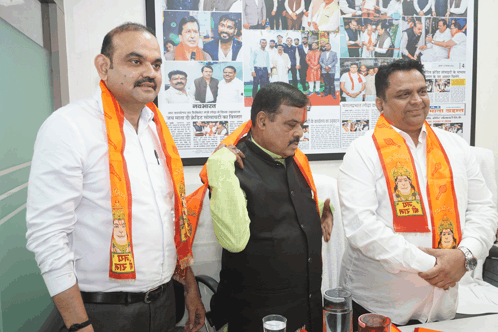 three men are standing in front of a wall with a picture of a man with a mustache