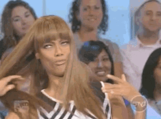 a woman in a wig is making a funny face in front of a group of people .
