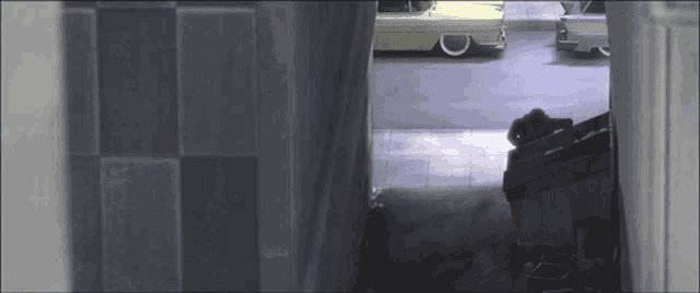 a few cars are parked in a garage with a man sitting on the ground