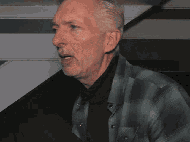 a man wearing a plaid shirt and black turtleneck