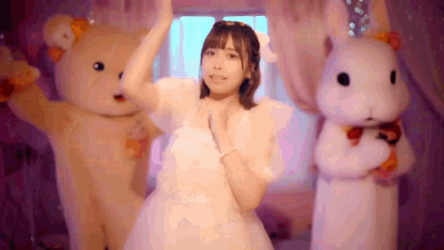 a girl in a white dress is dancing with two teddy bears and a white rabbit .