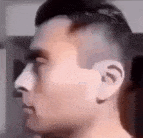 a close up of a man 's face with a shaved head and ear .