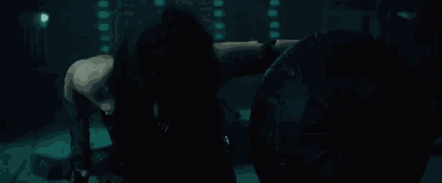 wonder woman is laying on the floor in a dark room with a shield .