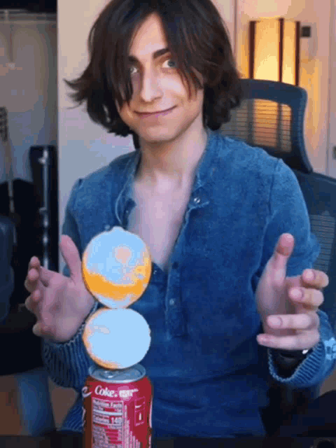 a man in a blue shirt holds a coke can in his hands