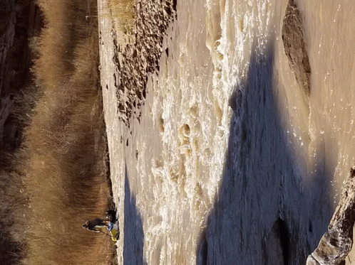 a person is standing on a rock near a waterfall