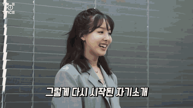 a woman in a suit is smiling in front of a window with twice written on it