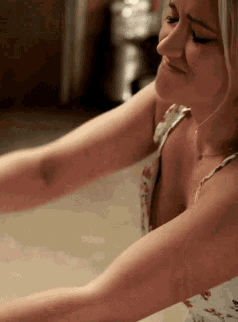 a woman in a floral tank top is smiling with her eyes closed
