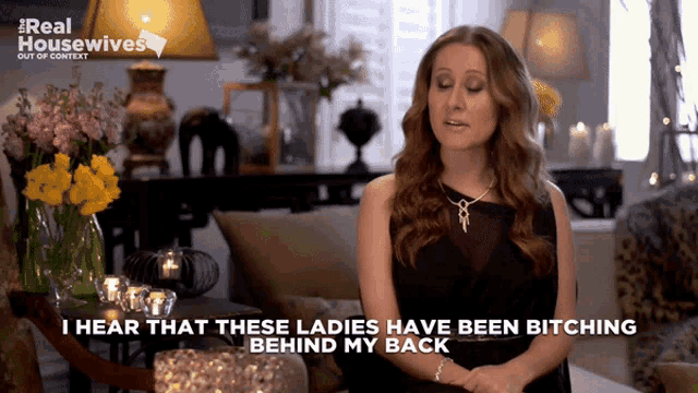 a woman is sitting in a living room and says i hear that these ladies have been bitching behind my back
