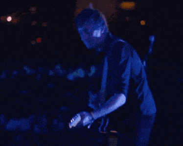 a man plays a guitar in front of a crowd