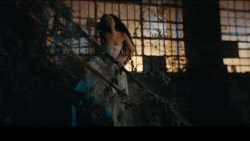 a woman in a white dress is walking down stairs