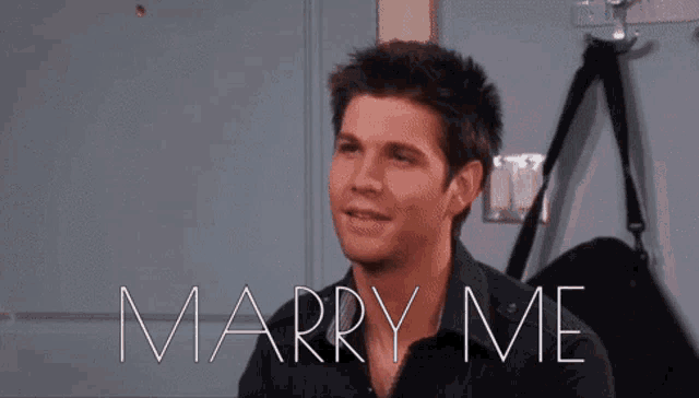 a woman sitting on a bed with the words marry me written on the screen