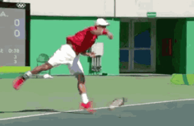 a tennis player in a red shirt and white shorts is jumping in the air