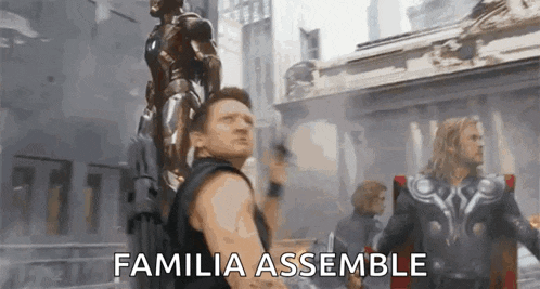 a man in a black tank top is holding a gun while standing next to a statue of iron man .