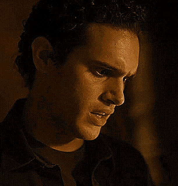 a close up of a man 's face with a serious look on his face in a dark room .