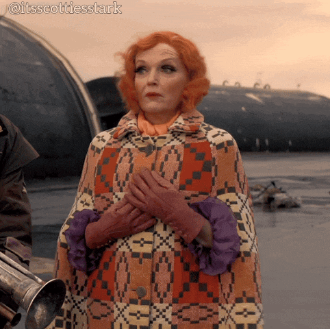 a woman with red hair is wearing a colorful coat