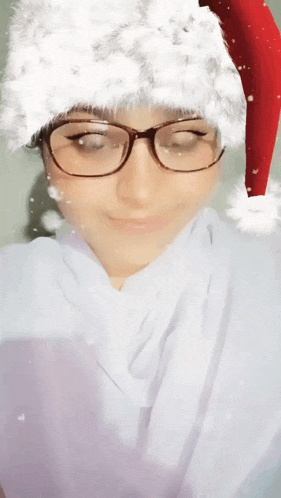 a woman wearing glasses and a santa hat is smiling