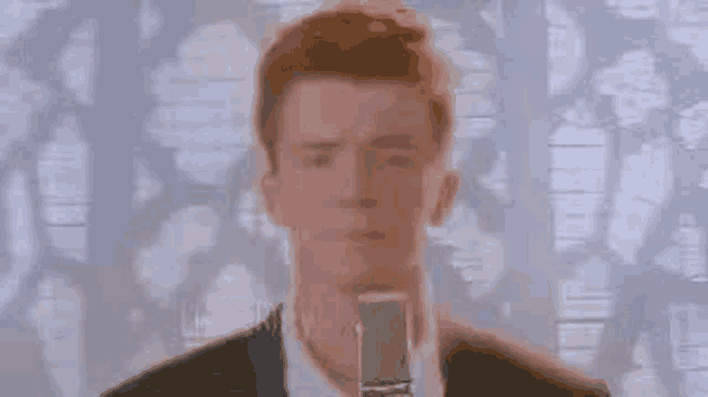 a man in a suit and tie is holding a microphone in front of him .