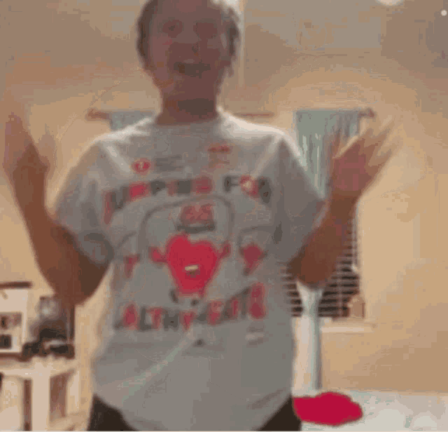 a woman wearing a jumping for saltines t-shirt is dancing in a room with her arms outstretched .