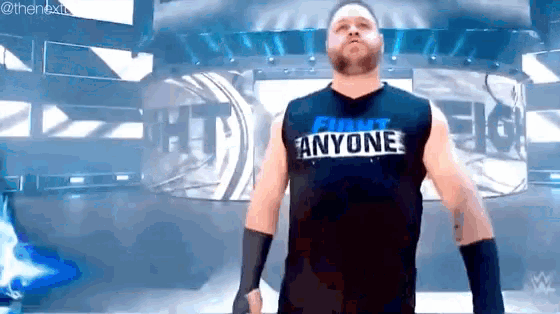a wrestler wearing a shirt that says funny anyone is standing in a ring .