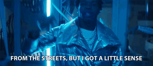 a man in a silver jacket with the words from the streets but i got a little sense next to him