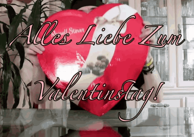 a person holding a heart shaped balloon with the words alles liebe zum valentinstag