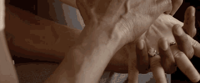 a woman with a ring on her finger is holding a man 's hand