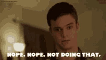 a young man is standing in a room and says nope nope not doing that .