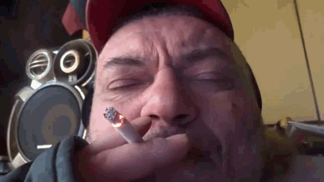 a man wearing a red hat is smoking a cigarette .