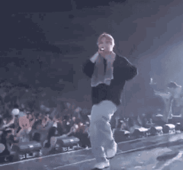 a man wearing a baseball cap and a grey hoodie is standing on a stage .