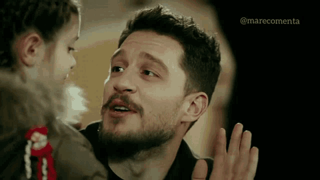 a man with a beard is talking to a little girl with the word marecomenta on the bottom