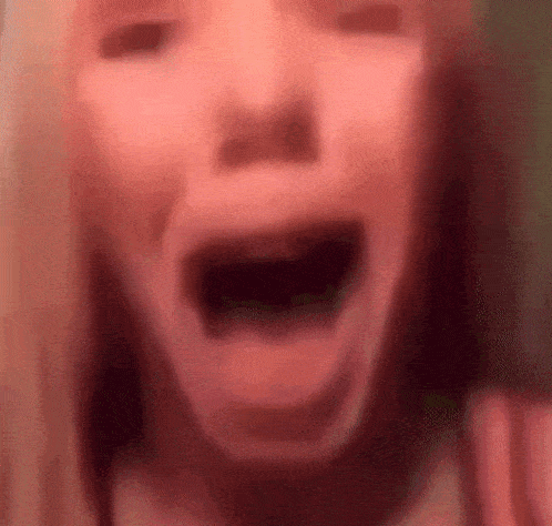 a close up of a girl 's face with her mouth open