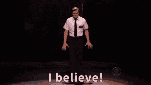 a man in a white shirt and tie is standing on a stage and says i believe .