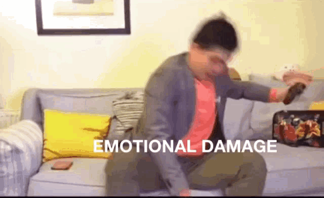 a man is sitting on a couch with emotional damage written on the bottom