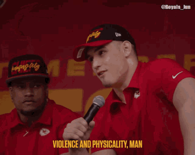 a man in a red shirt is holding a microphone and saying violence and physicality man