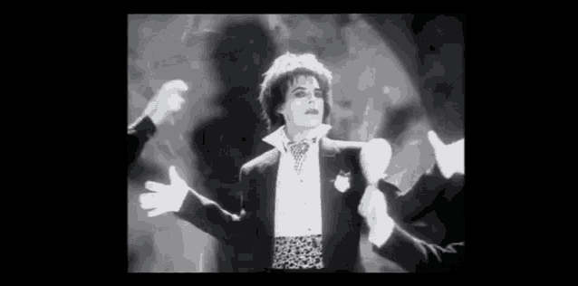 a man in a tuxedo and white gloves is surrounded by other men