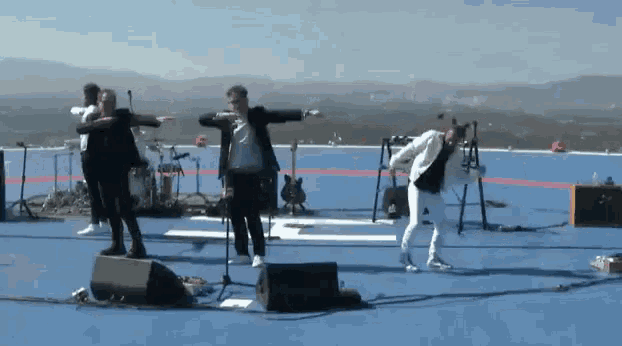a group of people are dancing on a stage with a guitar in the background