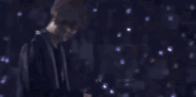 a man in a black suit is standing in a dark room holding a microphone .