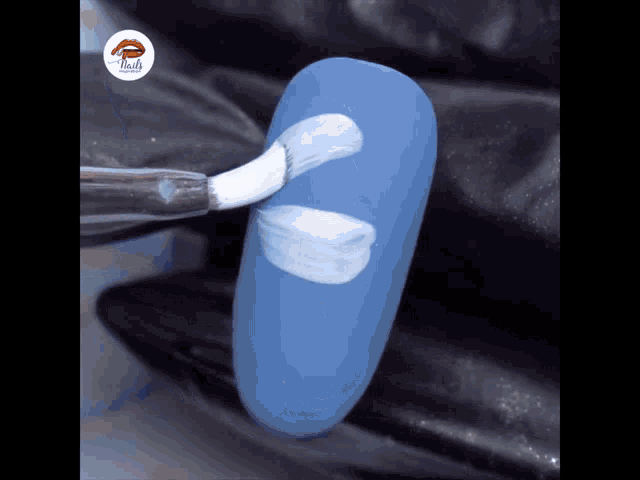 a blue nail is being painted with a white brush by nails
