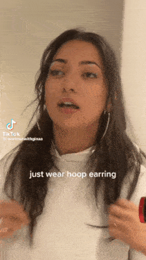 a woman is wearing hoop earrings and has a tiktok watermark on her face