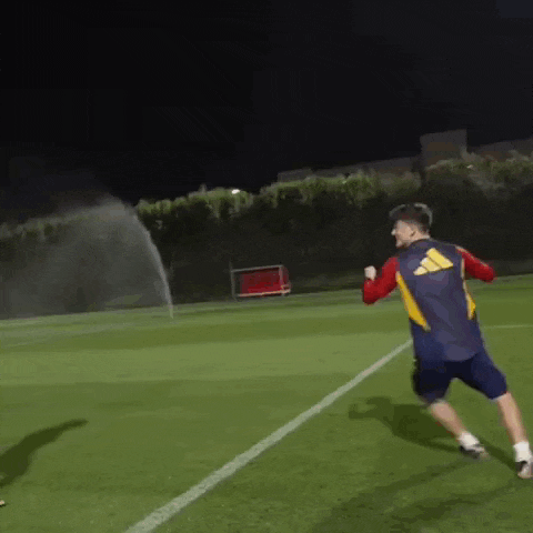 a man is running on a soccer field at night .