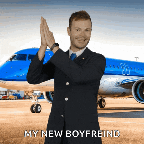 a man in a suit stands in front of a blue airplane with the words my new boyfreind below him