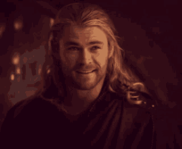 a man with long blonde hair and a beard smiles for the camera