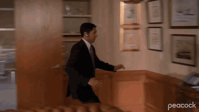 a man in a suit and tie is walking through a room with paintings on the wall .